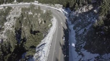 An aerial footage of an asphalt road in mountains surrounded by lush nature