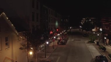 An aerial view of an empty street in the city with buildings and houses decorated with string of lights at night