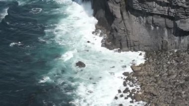 An aerial view of beautiful sea waves hitting the cliffs in Moher, Ireland