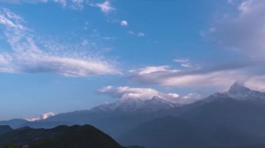 Güzel, kalın bulutlar, parlak mavi bir gökyüzünün altında, karlı dağların üzerinde süzülüyor.