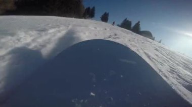A closeup of a snowboard nose sliding on the snow