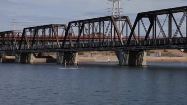 A scenic view of people paddling on the Tempe Town Lake, under a bridge in Arizona