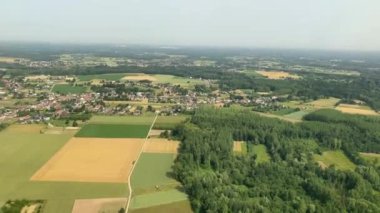 An aerial view of a town surrounded by green nature and agricultural fields