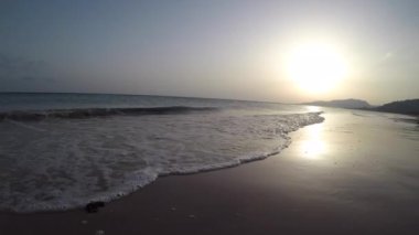 A man running on a sandy coast at sunset