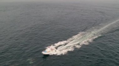 An aerial slow movement around floating boat in Cortez sea with dolphins