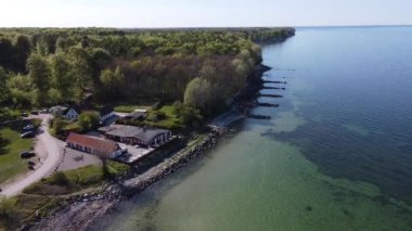 The 4K aerial drone footage moving along the coastal line of the beach and a resort house and a turquoise calm ocean view