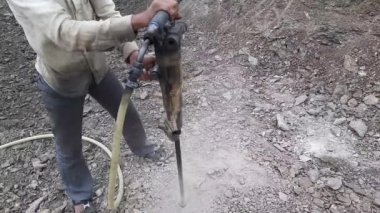 Dinamitle patlatmak için kaya delen bir işçi.