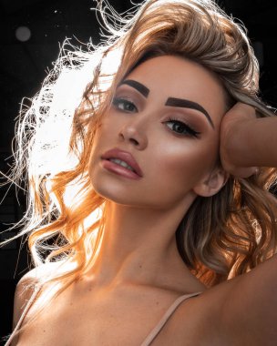 Uzun sarı kıvırcık saçlı güzel bir kızın dikey çekimi.