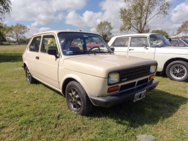 Eski bej Fiat 147. Üç kapılı hatchback 1981 kırsal kesimde. Güneşli bir gün. Doğa, çimen, ağaçlar. Klasik araba şovu..