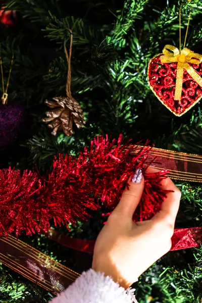 Vertical Closeup Female Hand Decorating Christmas Tree Red Shiny Garland — Zdjęcie stockowe