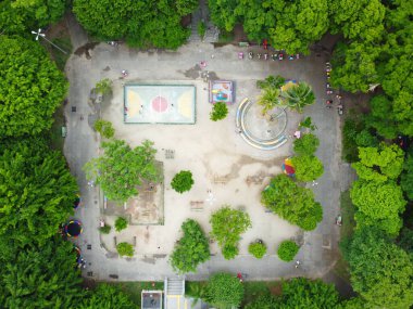 Yeşil ağaçlar ve bitkilerle çevrili bir parkın insansız hava aracı görüntüsü.