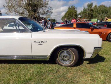 White old luxury Oldsmobile Ninety Eight sport coupe hardtop 1963 by GM  in the countryside. Side view. Badge. Nature, grass, trees. Classic car show.