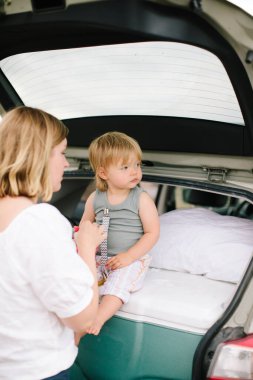 Kafkas anne ve kız çiftinin dikey bir görüntüsü. Arabalarında oturuyorlar.