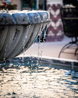 Süslü çeşme havuzundan akan su damlalarının dikey ve yakın çekim görüntüsü.