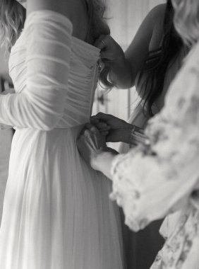 Gri tonlu bir gelin düğün gününde elbise giyiyor.