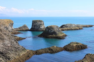 Dramatik volkanik kaya oluşumu, mavi ve turkuaz su, güneşli yaz günü, Arnarstapi, İzlanda