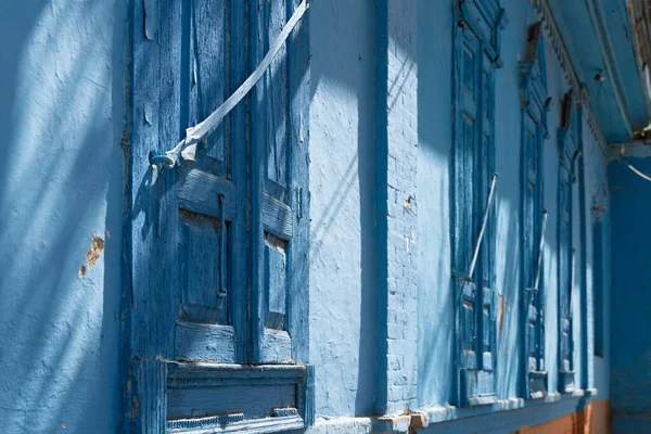 A side view of blue-painted closed wooden shutters of an old brick building