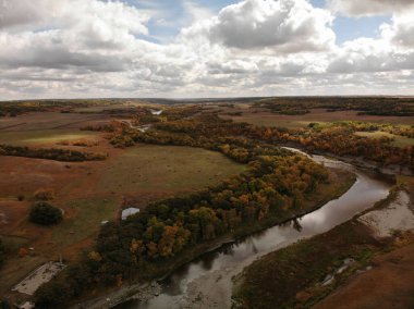 Bulutlu bir sabahta düzlüklerdeki kıvrımlı bir nehrin hava manzarası.