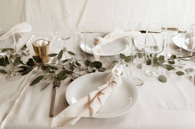 Restoranda bulaşık takımı ve düğün süslemeleri olan beyaz bir masa.