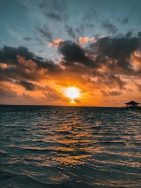 Sahilde Sunset 'in büyüleyici bir sahnesi. Kabini ve arka planda bulutlu bir gökyüzü var.