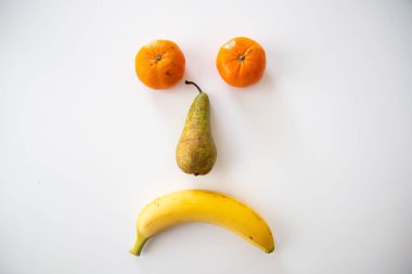 A closeup of various fruits isolated on white background. A sad face.