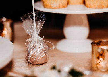 A selective focus shot of a sweet bun with white cream topping packed with a white ribbon