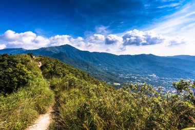 Dağ sıralarının güzel manzarası ve altında bulutlu gökyüzü olan bir kasaba.