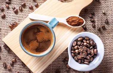 Yakın plan bir Americano ve tahtanın üzerinde kahve çekirdeği.