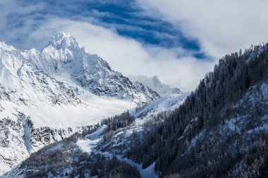 A beautiful view of rocky mountains covered by snow among fog