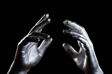 Elleri koyu arkaplanda metalik boyayla kaplıydı.