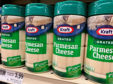 Bir perakende mağazasında üzerinde fiyat etiketleri olan rendelenmiş parmesan peyniri şişelerinin yakın çekimi.