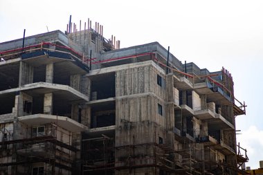 A beautiful shot of a high building under construction with metal equipment against a light sky