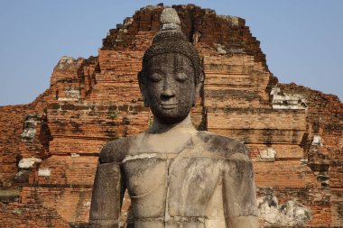 Kutsal bir kırmızı tuğla binanın arka planında Buda heykelinin yakın plan fotoğrafı..