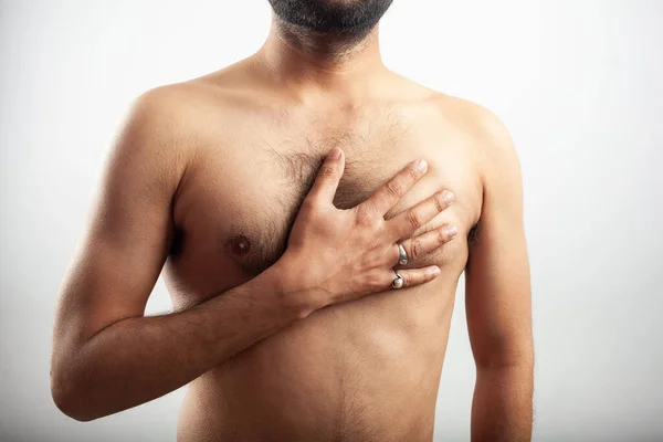 indian man hiding his chest hair in white background, chest pain due to heart attack