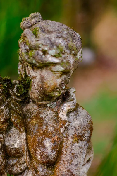 A mossy and worn down statue in a garden