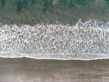 Kosta Rika 'da kumlu bir sahilde yumuşak okyanus dalgalarının hava manzarası.