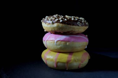 Koyu arkaplanda bir sütundaki çeşitli renkli çörekleri kapat