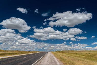Wyoming 'de bulutlu mavi gökyüzüne karşı bir tarlanın ortasında açık bir yol