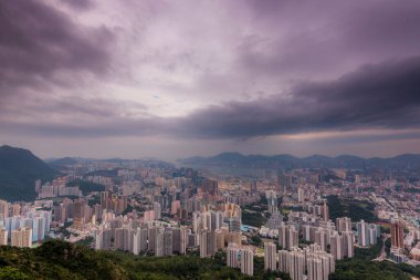 Kowloon şehri, Hong Kong, Çin 'de fırtınalı bulutlu bir gökyüzünün altında Lion Rock tepesinden duvarlarla çevrili.