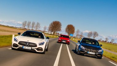 Hollanda 'da sonbahar ağaçlarıyla dolu 3 Mercedes AMG modeli yolda ilerliyor.