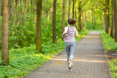 A young Caucasian female running on the path through the forest