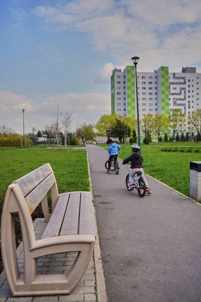 Two Boys Riding Bikes Footpath Park Bench Leading Apartment Block — Stockfoto