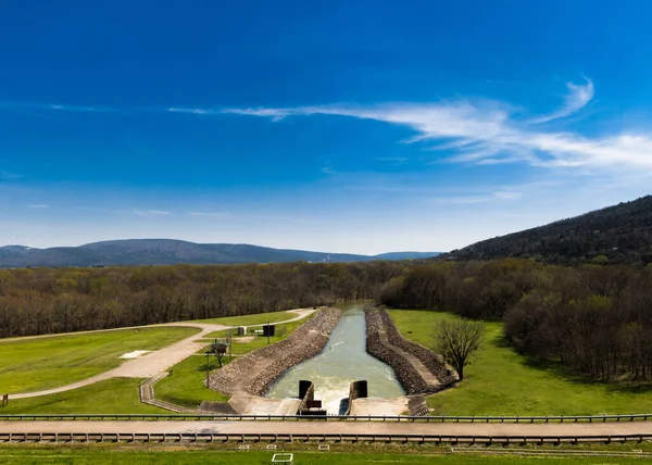 A beautiful view of a rolled earth dam in a rural area on a sunny day