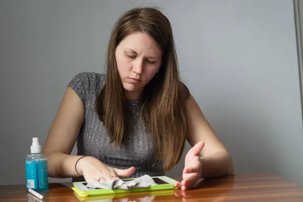 A close upwoman cleaning the screen of a tablet with special liquids