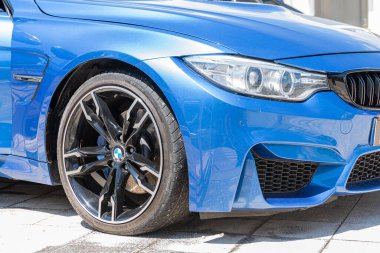 The frontside of a Blue BMW M4 Competition Coupe car on a sunny day