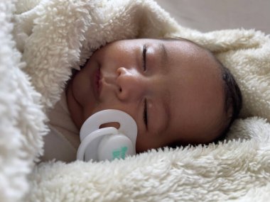 Beyaz bir çarşafın üzerinde uzanmış tatlı, huzurlu bebek. İçeride gündüz uykusunun tadını çıkar.