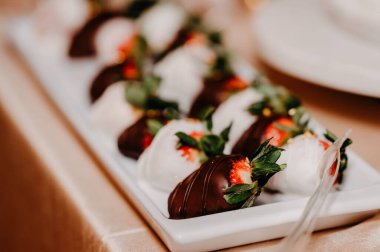 A closeup shot of brown and white chocolate-dipped strawberries on a white plate