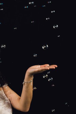 Siyah arka planda yüzen, dokunulabilir kabarcıklara işaret eden düz elli bir kadının kolu.
