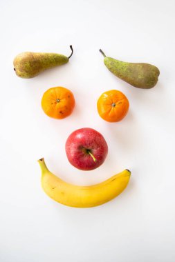 Beyaz arka planda izole edilmiş çeşitli meyvelerin dikey yakın çekimi. Gülen surat..