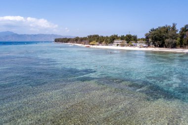 Arkasında kristal berrak su ve kumlu kıyılarla huzurlu bir deniz manzarası.